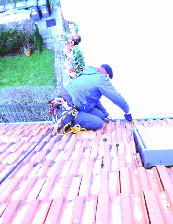 Person auf dem Dach, arbeitet an der Regenrinne